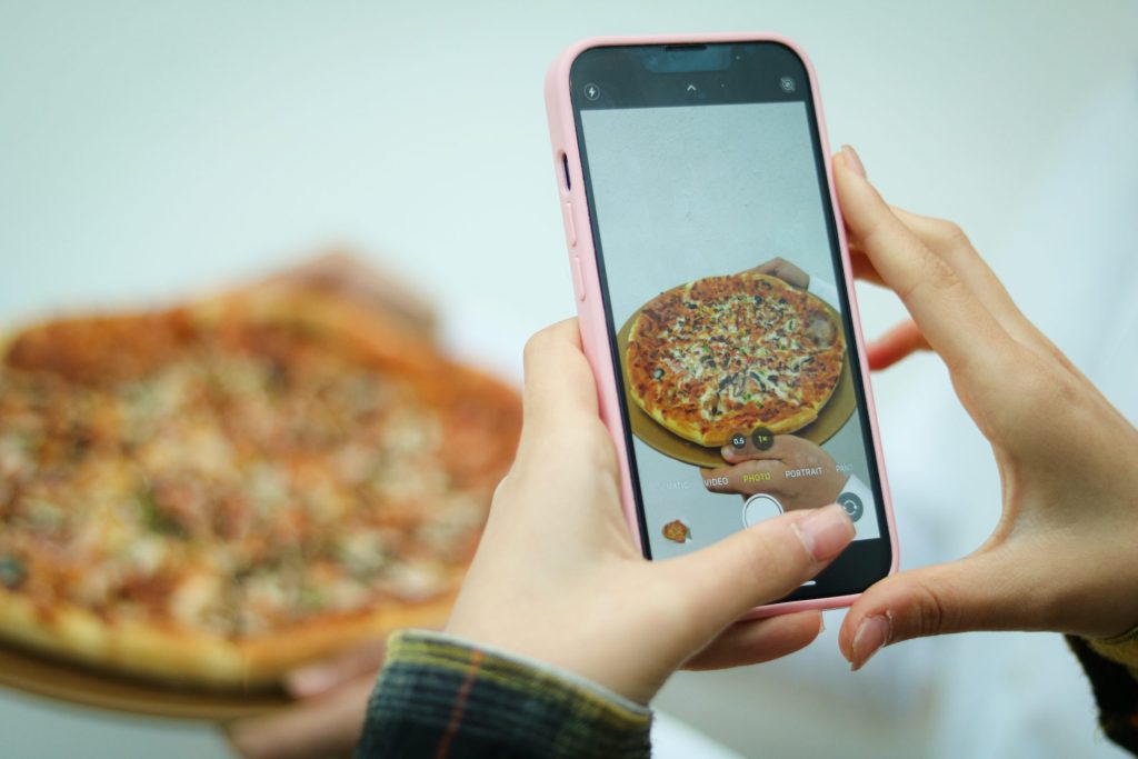 une femme prenant une photo d'une pizza avec son téléphone